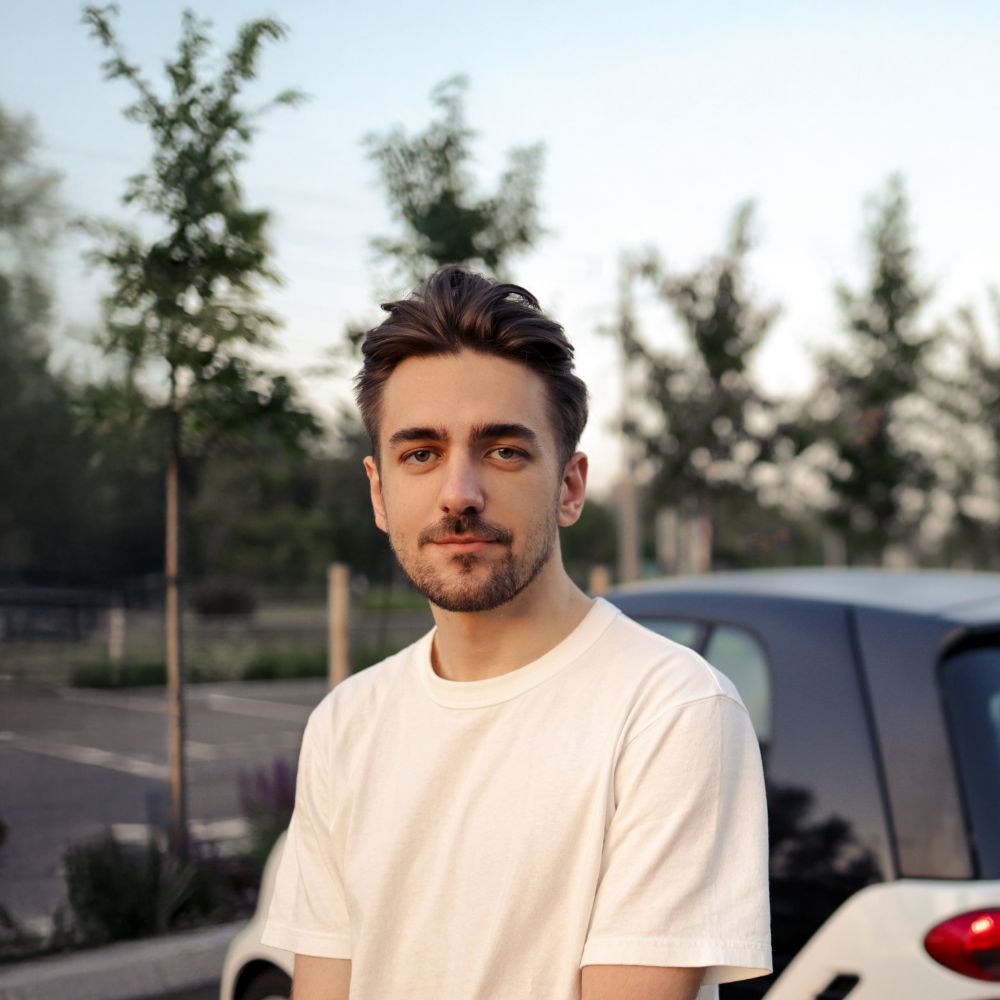 Young Driver standing next to white Smart car